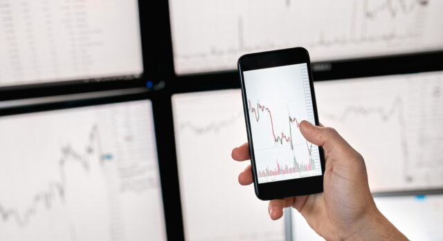 株価チャートの変動をスマホで確認する男性